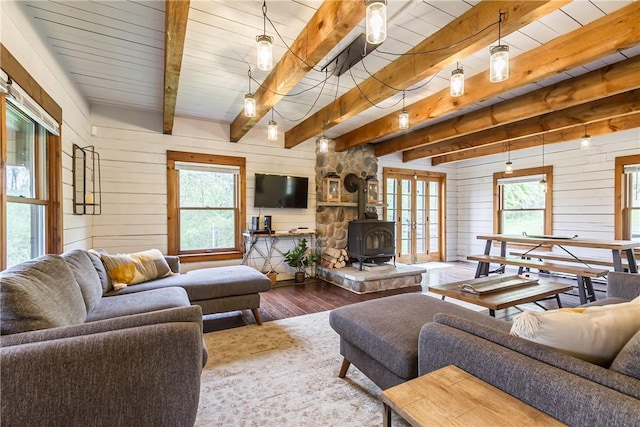 living room featuring a wood stove, wood finished floors, beam ceiling, and wood walls
