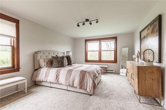 bedroom featuring baseboard heating, multiple windows, and light carpet