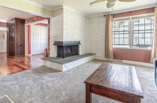 unfurnished living room with carpet floors, a ceiling fan, ornamental molding, a fireplace, and baseboards