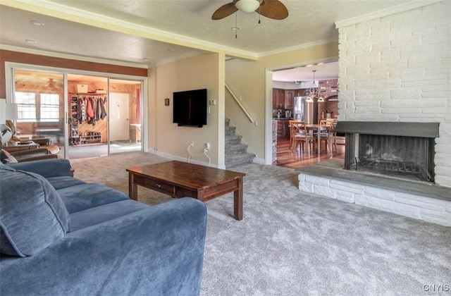living room with carpet, stairs, ornamental molding, ceiling fan, and baseboards