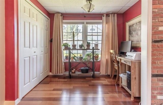 office with wood-type flooring and a paneled ceiling