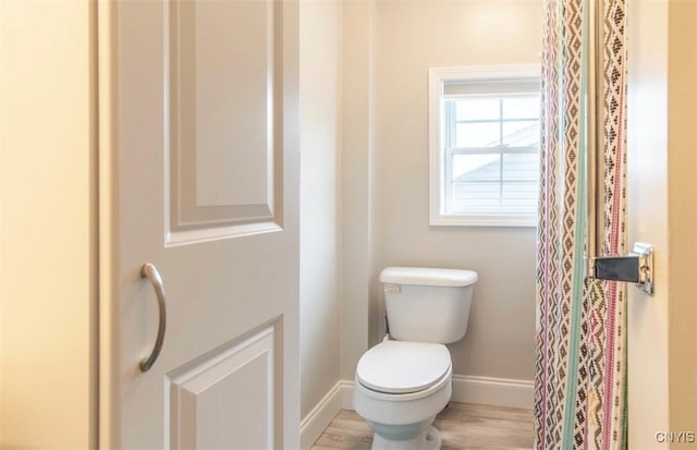 bathroom with baseboards, toilet, and wood finished floors