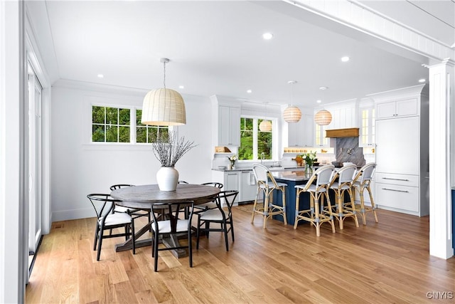 dining room featuring healthy amount of natural light, light wood-style flooring, recessed lighting, ornamental molding, and decorative columns