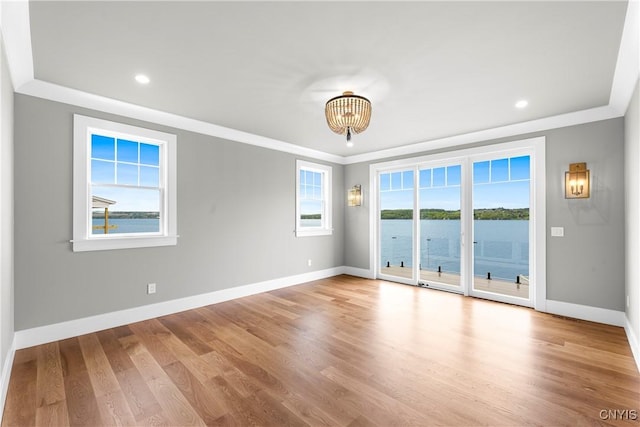 unfurnished room featuring plenty of natural light, baseboards, wood finished floors, recessed lighting, and crown molding