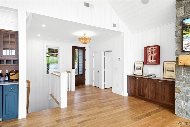 bar featuring light wood finished floors and vaulted ceiling