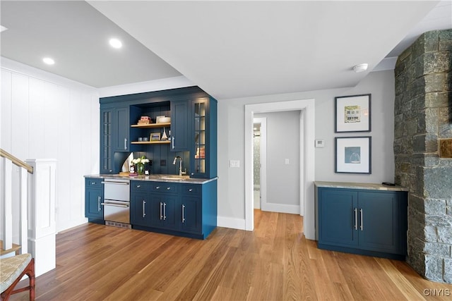bar area featuring stairs, light wood-style flooring, a sink, stainless steel dishwasher, and baseboards