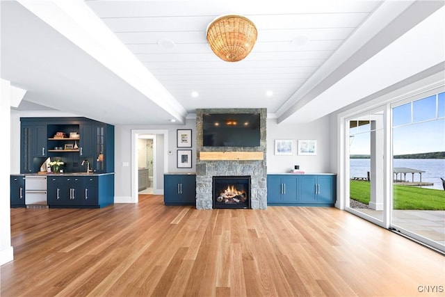 unfurnished living room featuring light wood-type flooring, a fireplace, a sink, and baseboards