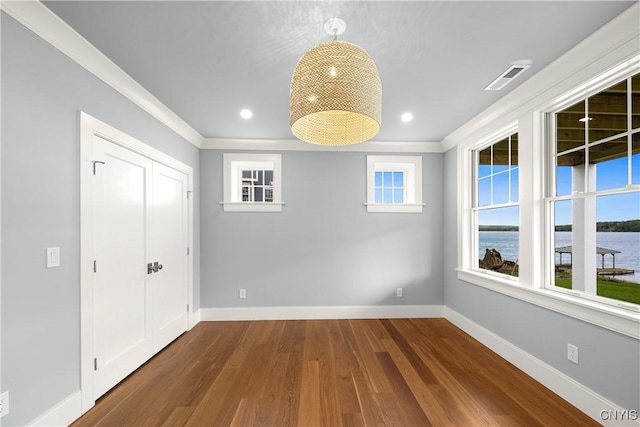 unfurnished dining area with wood finished floors, baseboards, crown molding, healthy amount of natural light, and recessed lighting