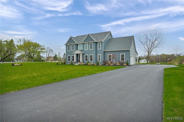 colonial home with a front lawn, a shingled roof, and driveway