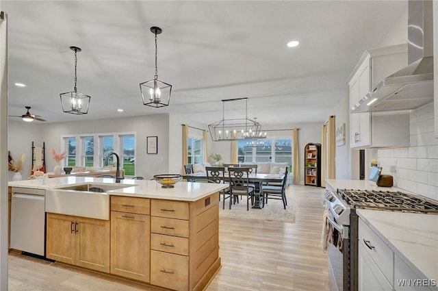 kitchen with gas range oven, stainless steel dishwasher, wall chimney range hood, light wood-type flooring, and decorative backsplash