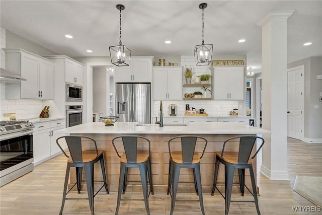 kitchen featuring appliances with stainless steel finishes, a sink, backsplash, light wood-type flooring, and recessed lighting