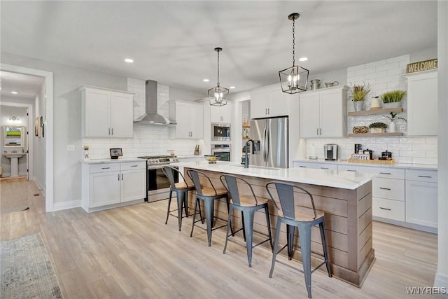 kitchen with wall chimney exhaust hood, appliances with stainless steel finishes, backsplash, recessed lighting, and a kitchen bar