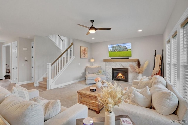 living area featuring stairway, a ceiling fan, a premium fireplace, baseboards, and recessed lighting
