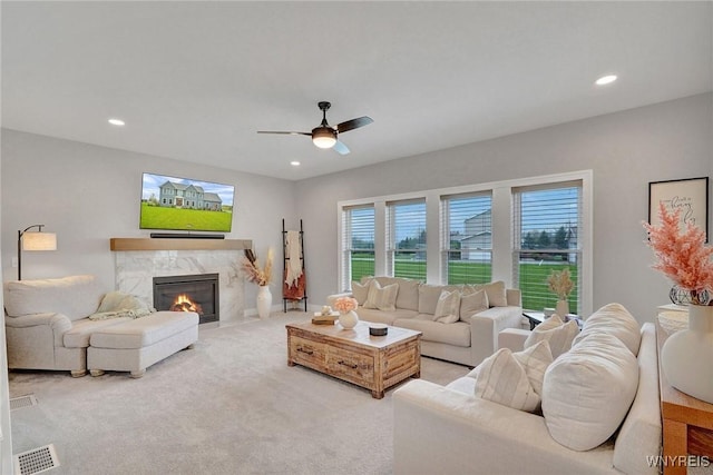 living room with ceiling fan, a high end fireplace, recessed lighting, and light carpet