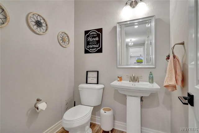 half bathroom featuring toilet, baseboards, and wood finished floors