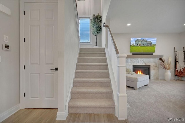 staircase with baseboards, wood finished floors, a fireplace, and recessed lighting