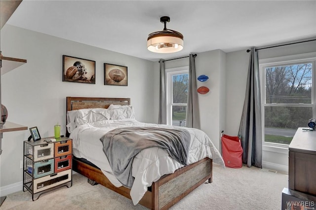 bedroom featuring multiple windows, light colored carpet, and baseboards