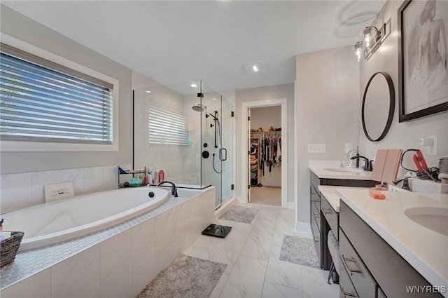 bathroom featuring a garden tub, a shower stall, marble look tiles, vanity, and a spacious closet