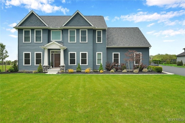 view of front of house with a front lawn and a shingled roof