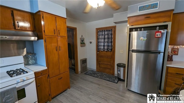 3738 E Lake Rd, Dunkirk-Town, NY 14048 - kitchen with freestanding refrigerator, white gas stove, under cabinet range hood, and brown cabinetry