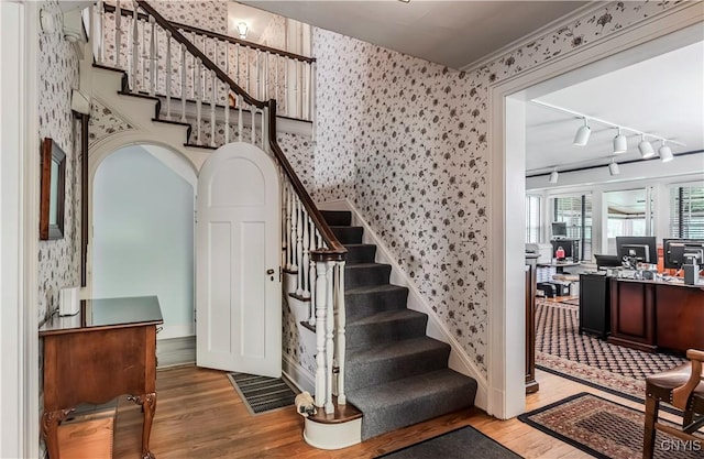 2810 Genesee St, Utica, NY 13502 - staircase featuring wallpapered walls, wood finished floors, rail lighting, and baseboards