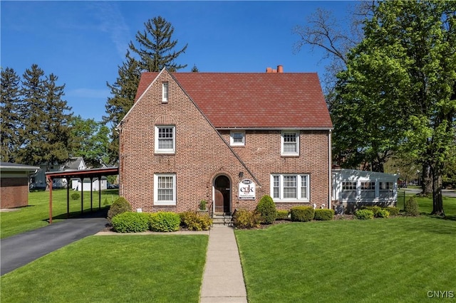 2810 Genesee St, Utica, NY 13502 - tudor-style house featuring a front lawn, brick siding, driveway, and an attached carport