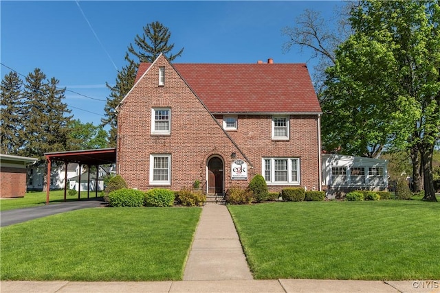 2810 Genesee St, Utica, NY 13502 - english style home featuring brick siding, a front lawn, an attached carport, and driveway