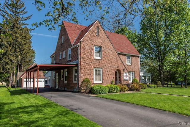 2810 Genesee St, Utica, NY 13502 - tudor house with a carport, an outdoor structure, a front lawn, brick siding, and asphalt driveway