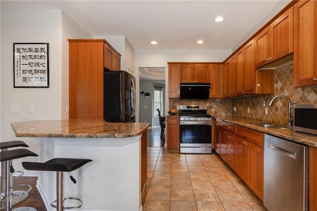 318 Wexford Ln, Horseheads, NY 14845 - kitchen with stainless steel appliances, a sink, a breakfast bar area, backsplash, and brown cabinetry