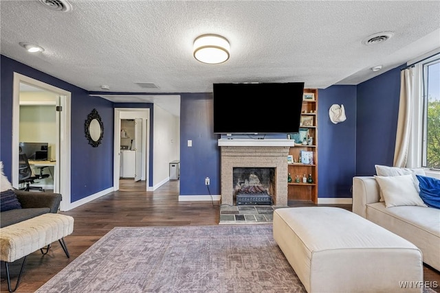 living area featuring baseboards, wood finished floors, a textured ceiling, and a fireplace