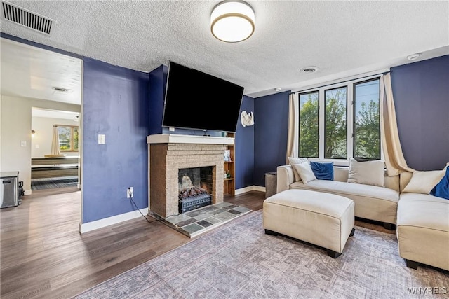living area with wood finished floors, a textured ceiling, baseboards, and a fireplace