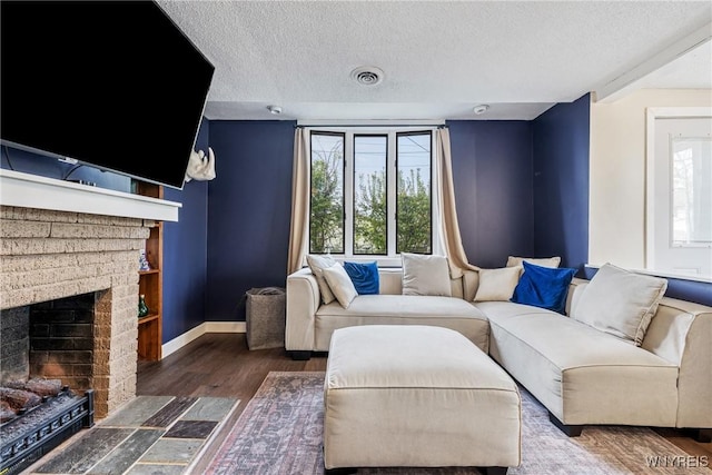 living room featuring a textured ceiling, wood finished floors, a fireplace, and baseboards