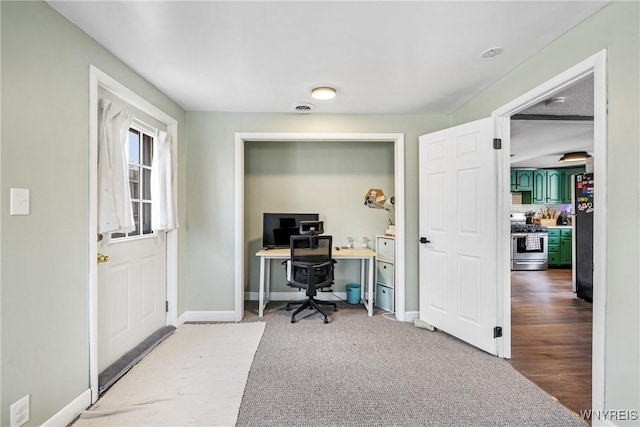 home office with baseboards and light carpet