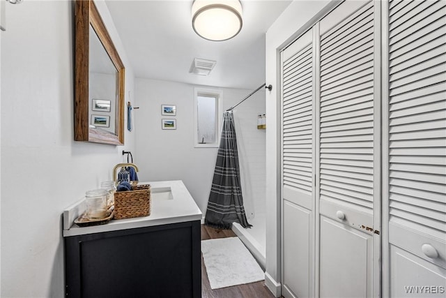 bathroom featuring a closet, wood finished floors, curtained shower, and vanity