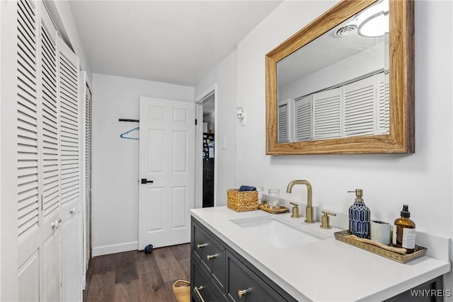 bathroom with wood finished floors, vanity, and baseboards