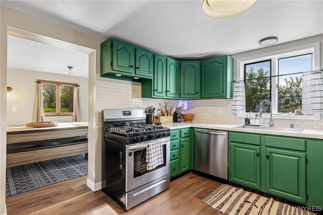 kitchen featuring appliances with stainless steel finishes, a sink, wood finished floors, and tasteful backsplash