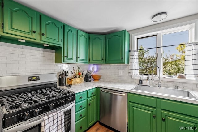 kitchen with appliances with stainless steel finishes, a sink, light countertops, decorative backsplash, and plenty of natural light