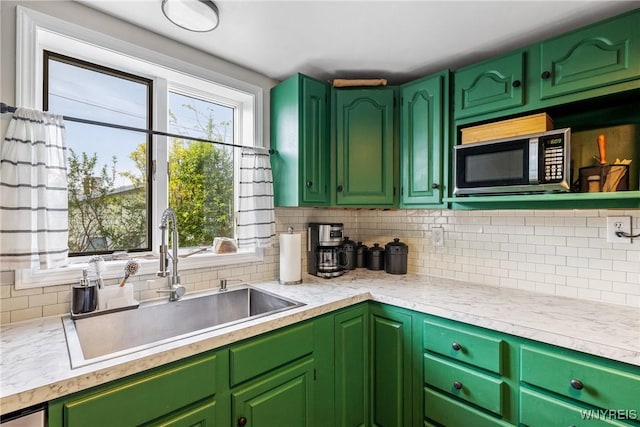 kitchen featuring stainless steel microwave, a sink, decorative backsplash, and light countertops