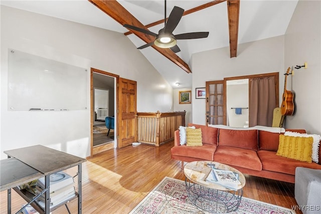 living room with ceiling fan, beam ceiling, light wood-style floors, high vaulted ceiling, and bar area