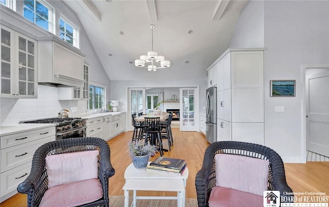3 Maple Ave, Chautauqua, NY 14722 - kitchen with stainless steel appliances, high vaulted ceiling, glass insert cabinets, a chandelier, and light wood-style flooring