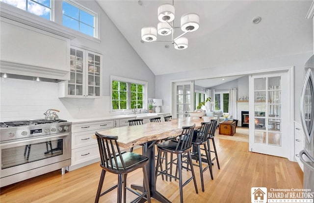 3 Maple Ave, Chautauqua, NY 14722 - dining room with light wood-style floors, a chandelier, high vaulted ceiling, and a glass covered fireplace