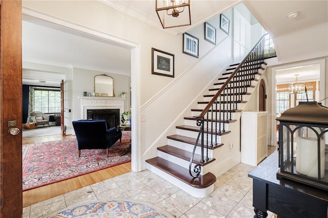 stairway featuring a chandelier, ornamental molding, a fireplace, and tile patterned floors