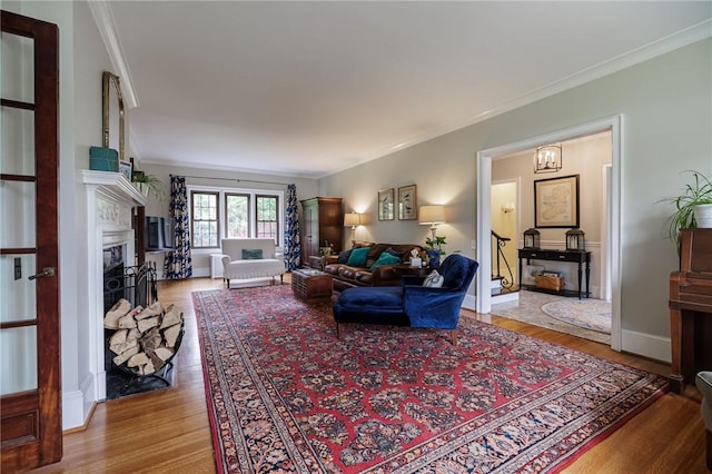 living area with a fireplace, crown molding, wood finished floors, and baseboards