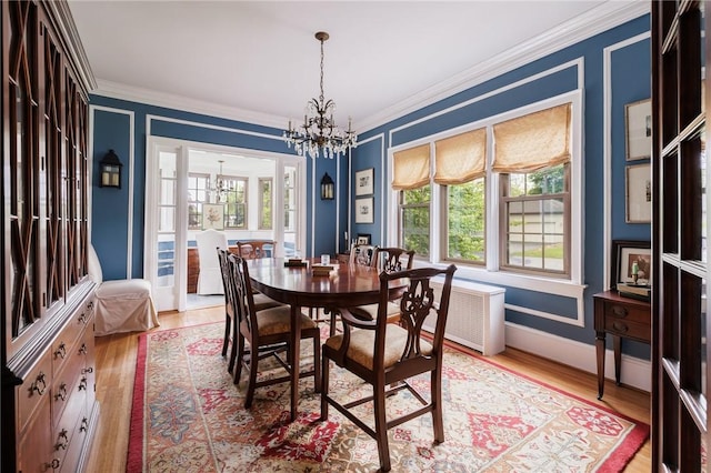 dining room with a chandelier, ornamental molding, plenty of natural light, and light wood-style floors