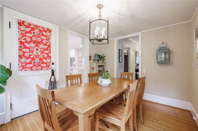 dining area featuring light wood-style flooring, a chandelier, and baseboards