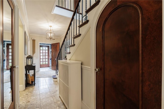 entrance foyer featuring ornamental molding, stairs, a chandelier, french doors, and arched walkways