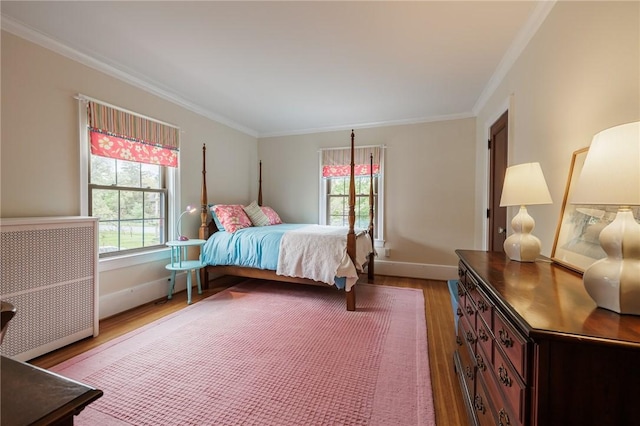 bedroom featuring wood finished floors, crown molding, multiple windows, and baseboards