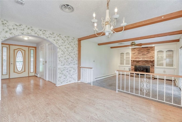 unfurnished living room featuring wallpapered walls, wood finished floors, arched walkways, baseboard heating, and a ceiling fan