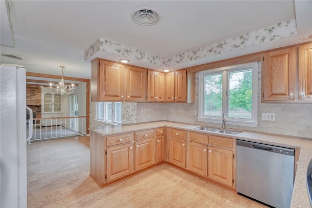 kitchen featuring stainless steel dishwasher, a sink, light wood-style flooring, and light countertops