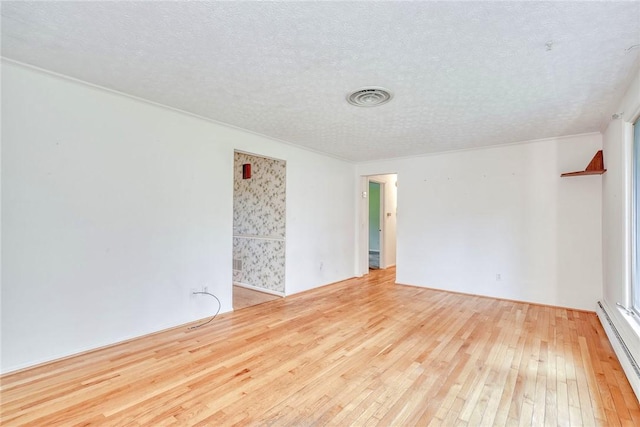 spare room featuring baseboard heating, wood-type flooring, and a textured ceiling
